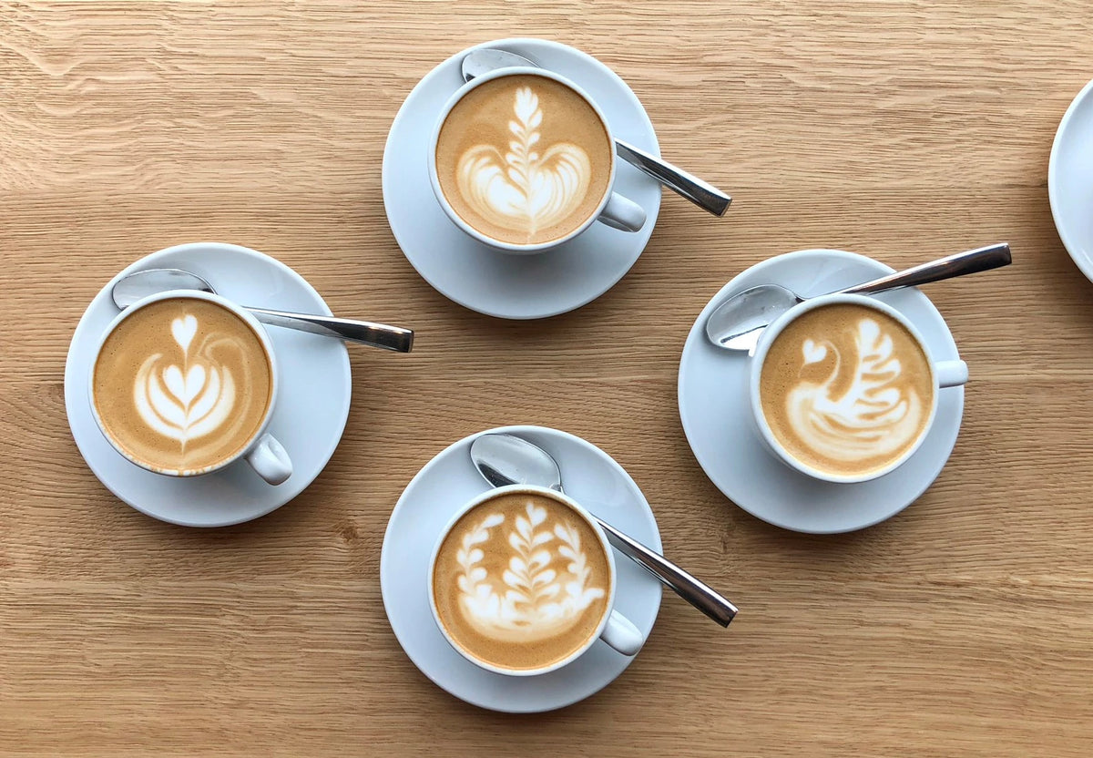 Vier Latte Art Tassen mit verschiedenen Mustern von oben – Latte Art Kaffeespezialitäten bei 19grims.com Roasters Berlin