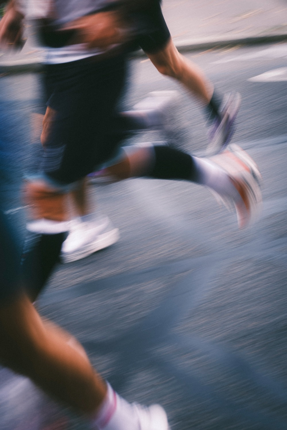 Bewegungsunscharfe Nahaufnahme laufender Beine in Laufschuhen auf Asphalt – 19grams The Blue Line, Sonderedition zum Berlin-Marathon