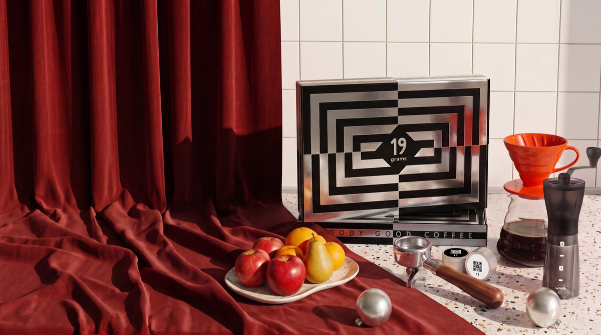 19grams Kaffee Adventskalender 2026 – Website-Banner mit Kalenderbox, Handmühle, Handfilter und Obstschale vor rotem Vorhang