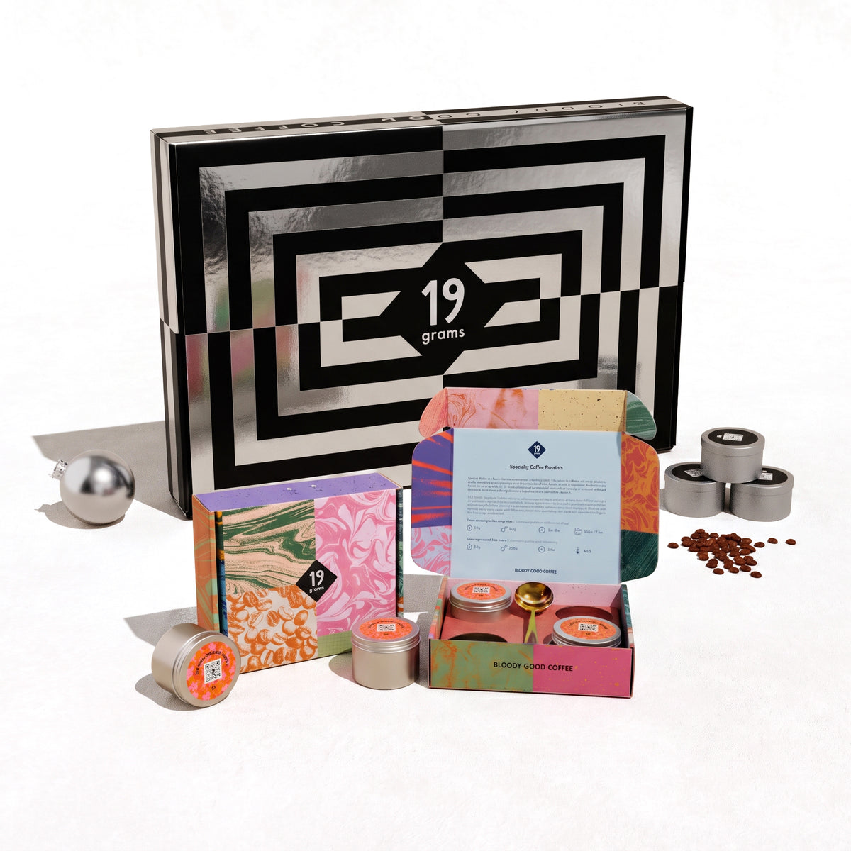 19grams Adventskalender 2026 Value Pack – Produktfoto der schwarz-weiß gemusterten Kalenderbox mit geöffneter Box, silbernen 50g-Dosen und Kaffeebohnen