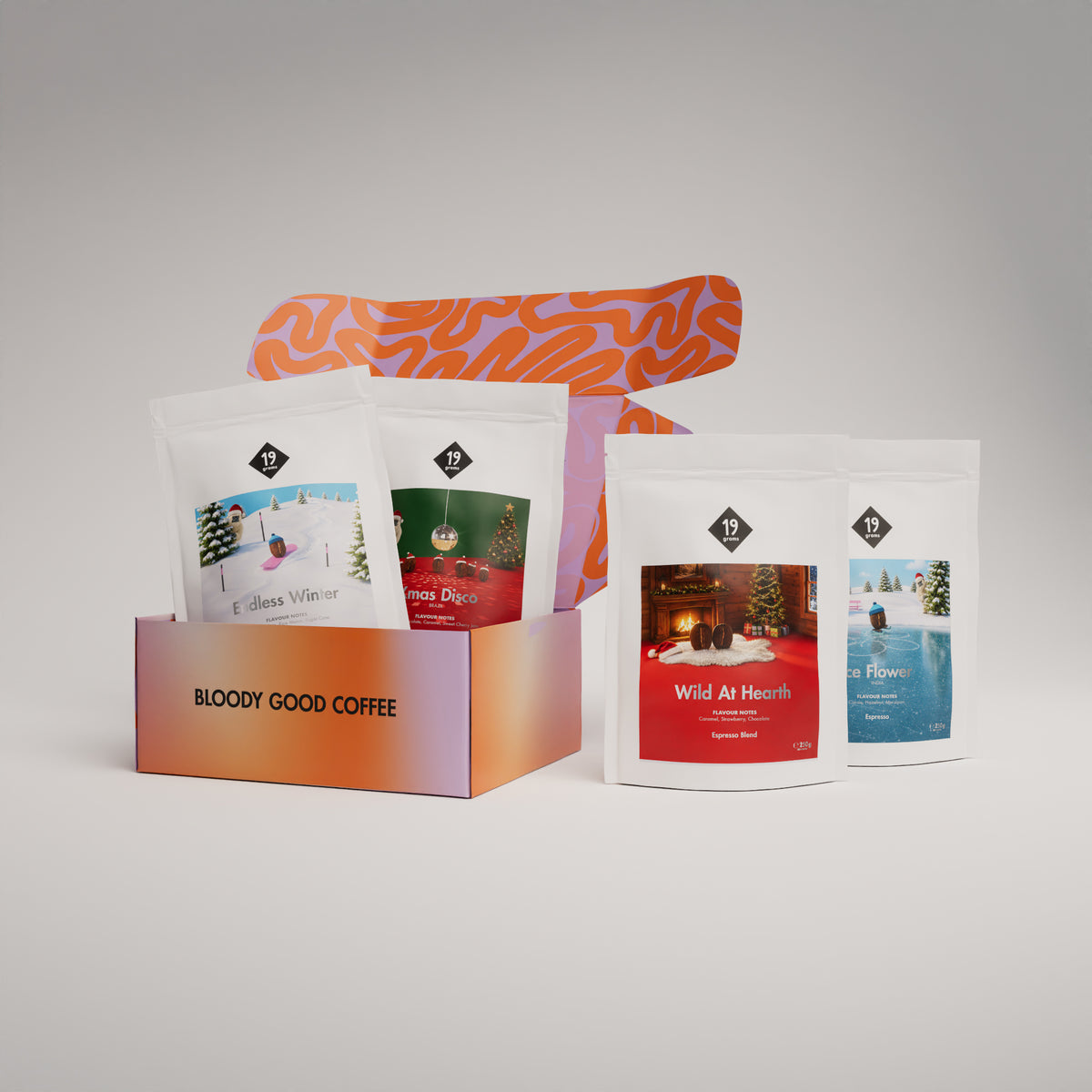 19grams Classic Adventskalender Espresso – Produktmockup mit oranger Geschenkbox „Bloody Good Coffee“ und vier Kaffeebeuteln der Serie (Endless Winter, Xmas Disco, Wild At Hearth, Ice Flower)