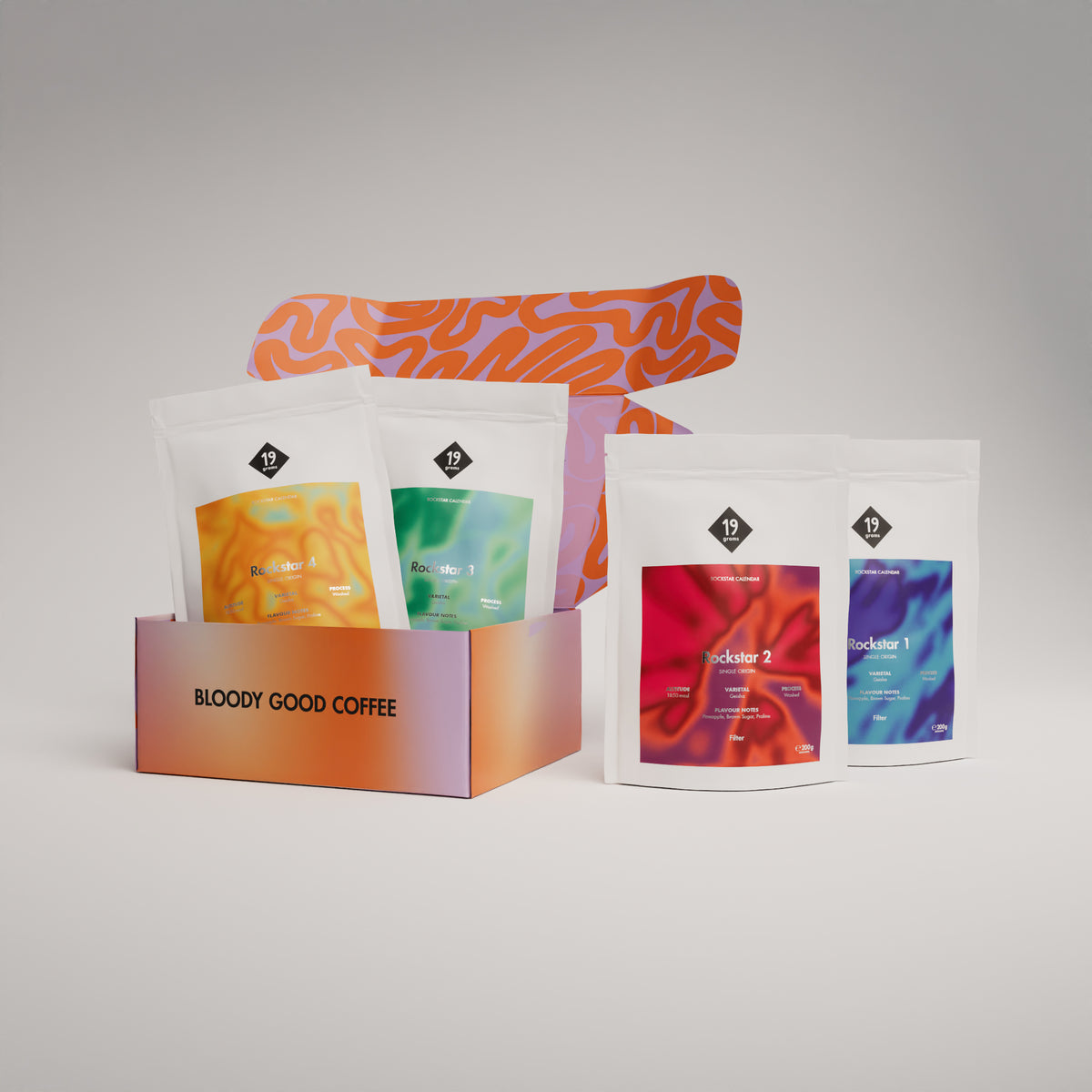 19grams Rockstar Kaffee Kalender 2026 Filter – Produktmockup mit oranger Geschenkbox „Bloody Good Coffee“ und den vier bunten Kaffeebeuteln Rockstar 1 bis 4, Filterkaffee 200g, Kaffeerösterei Berlin