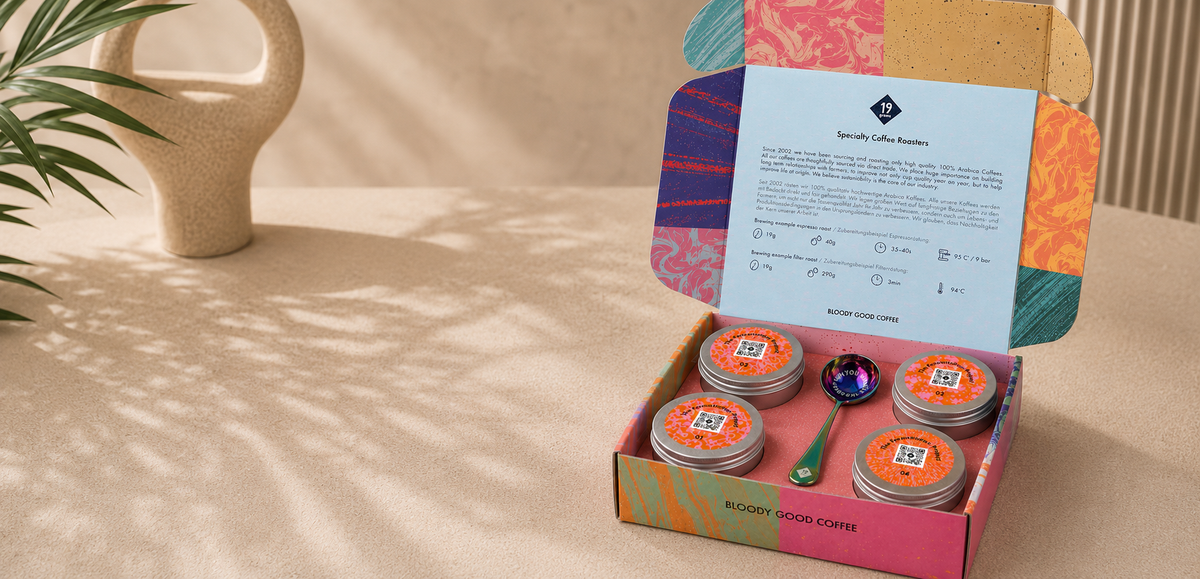 19grams The Fermentation Project Kaffee Kit – Produktmockup der geöffneten marmorierten Geschenkbox mit vier silbernen Kaffeedosen, Löffel und Infokarte vor beigem Hintergrund